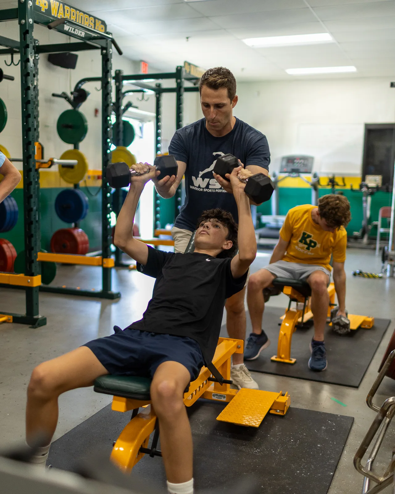 Coach guiding a dumbbell press