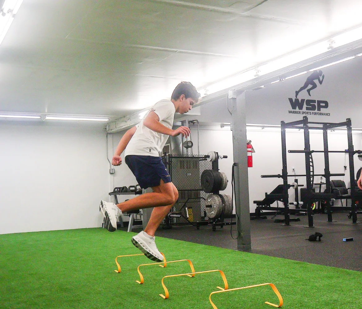 Athlete clearing mini hurdles on the turf at Warrior Sports Performance